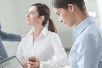 Business professionals analyze data on laptops during a meeting, highlighting vet compliance updates.