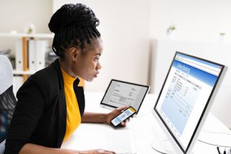 A woman uses multiple devices for online banking, reflecting the need for authentic assessment in vet sector learning.